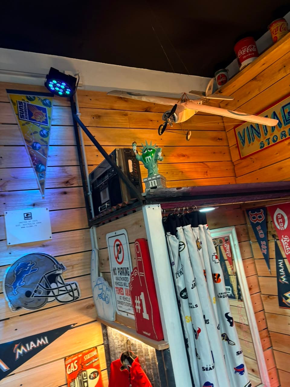 Techo del local con una avioneta de madera, banderines de los Red Sox y los Miami Marlins y una figura de la Estatua de la Libertad